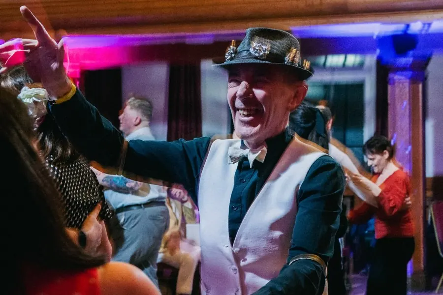 A dancer in a decorated hat laughing mid-dance