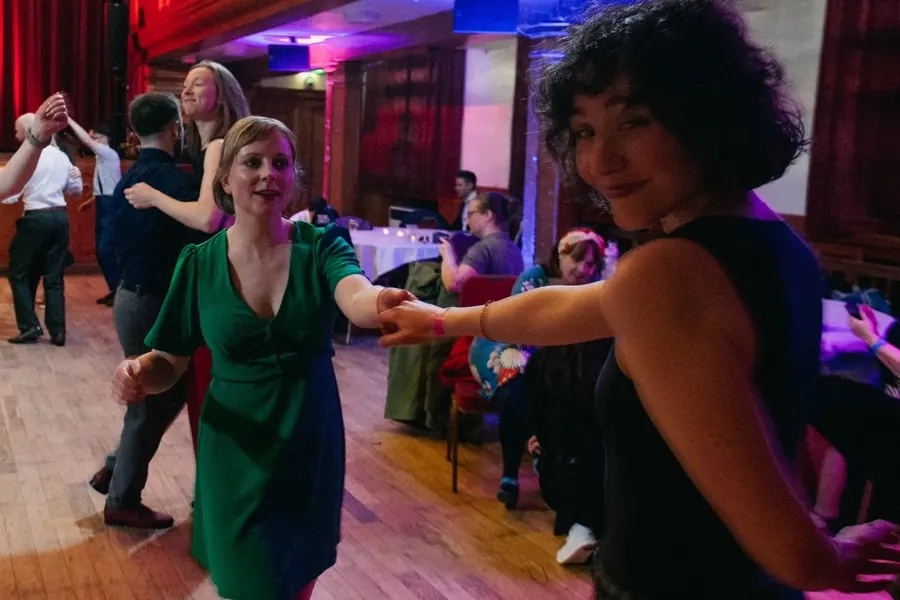 Two dancers sharing a swing-out on the social floor